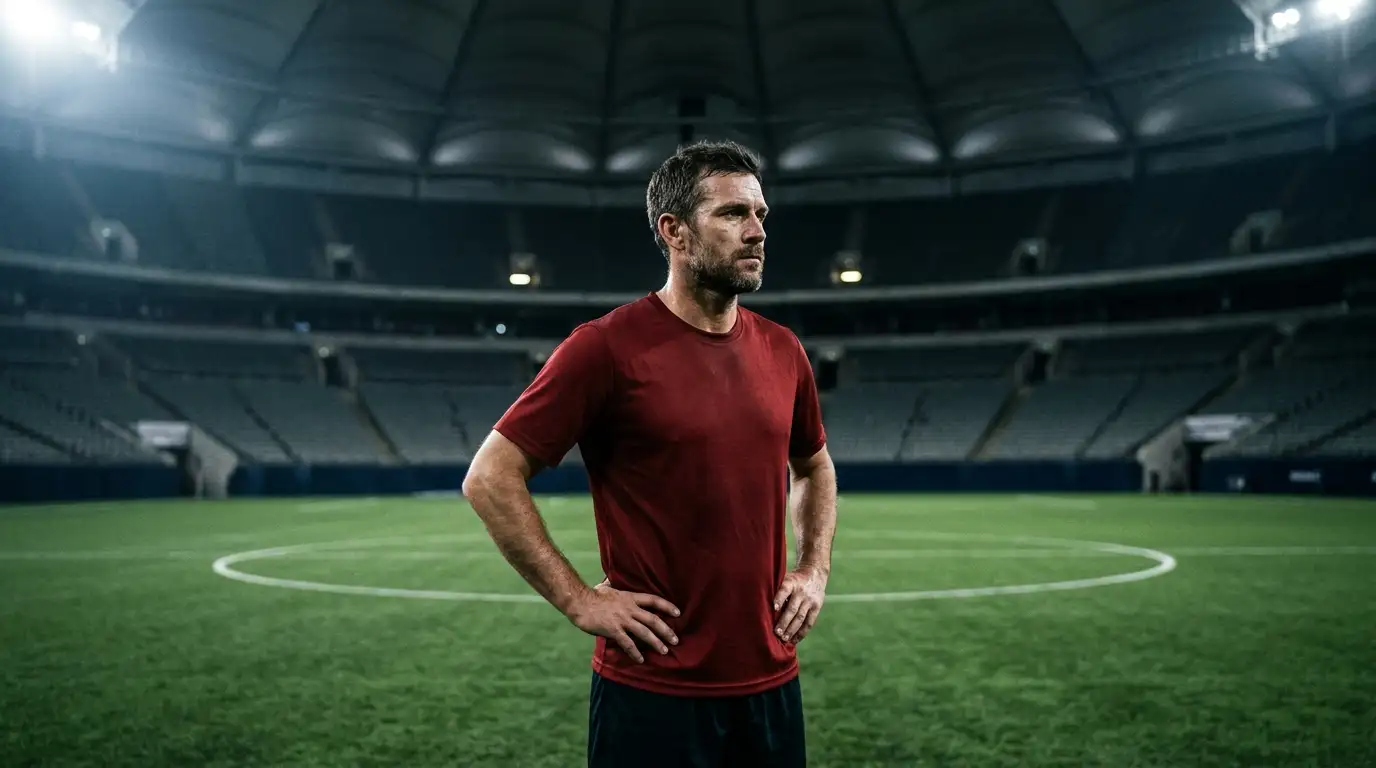 Un footballeur vétéran seul sur la pelouse, le regard concentré avant le coup d'envoi
